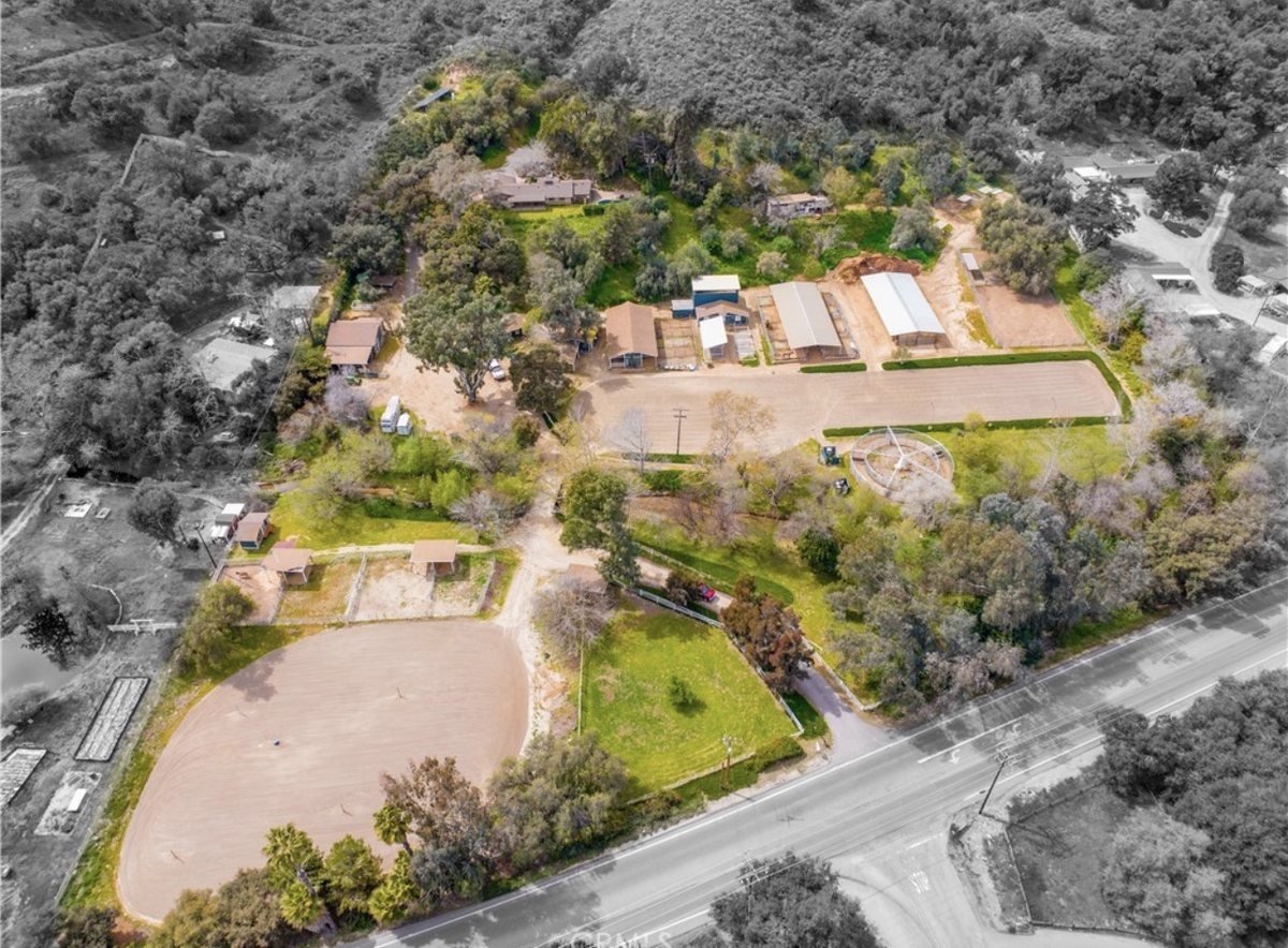 Overhead aerial of the Fallbrook horse property showing two sand arenas, covered barns and the residence among oak trees