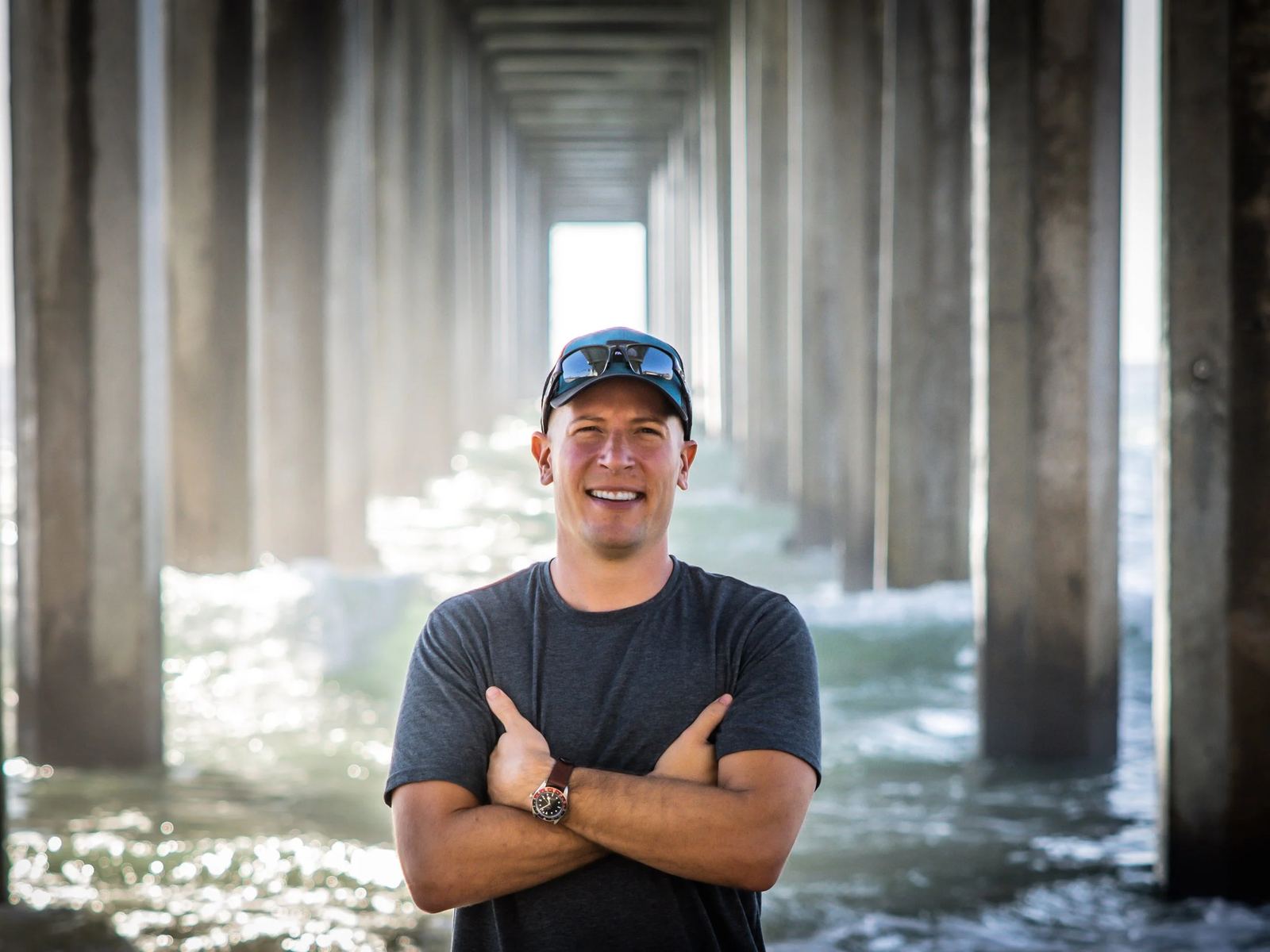 Stephen Resendes standing under a pier at the waterline, arms crossed
